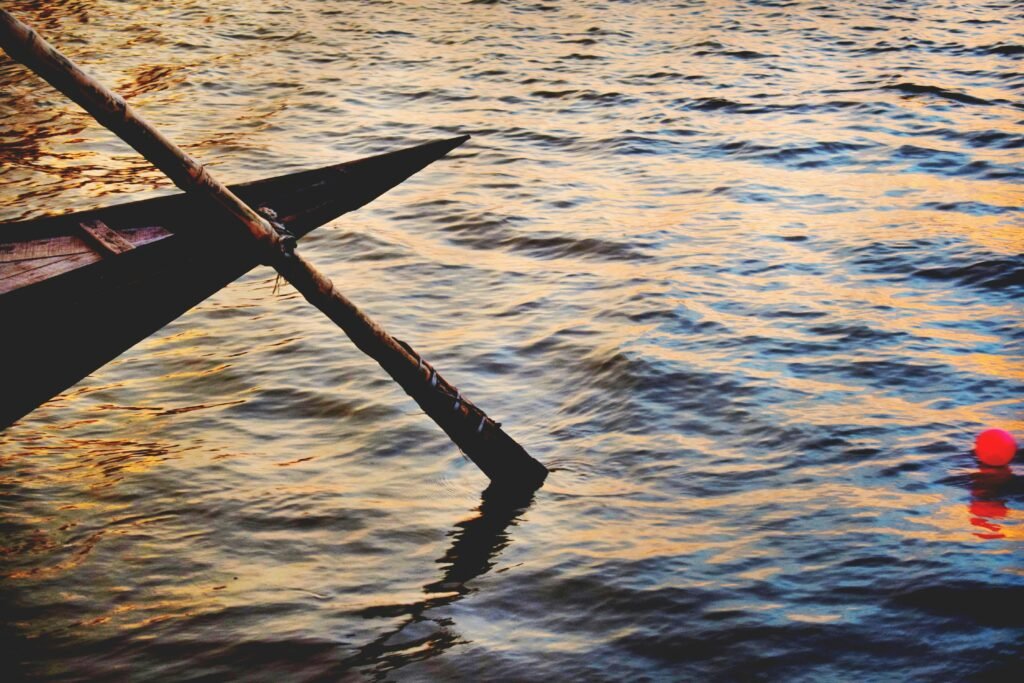 A serene scene of a wooden rowboat and vibrant water reflections at sunset.